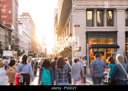 Vielfältige Gruppe von anonymen Menschen zu Fuß nach unten belebten Straße mit hellem Sonnenlicht im Hintergrund in New York City glänzen Stockfoto