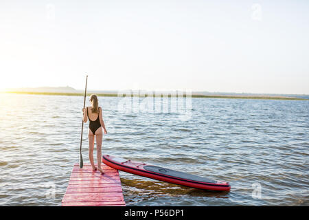 Frau mit paddleboard auf der Pier im Freien Stockfoto