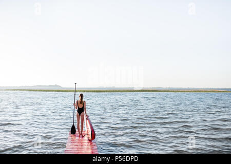 Frau mit paddleboard auf der Pier im Freien Stockfoto