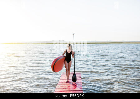 Frau mit paddleboard auf der Pier im Freien Stockfoto