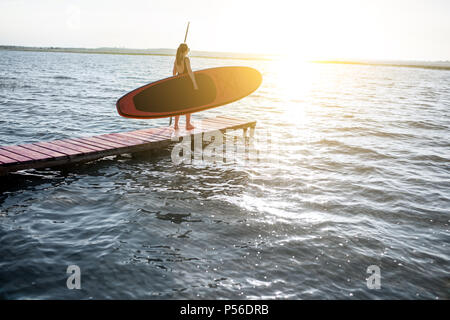 Frau mit paddleboard auf der Pier im Freien Stockfoto