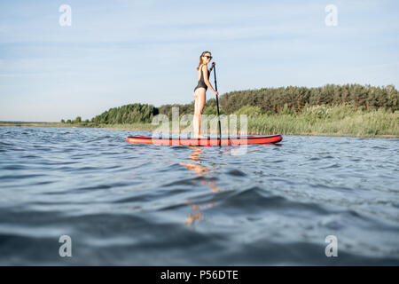 Frau paddleboarding auf dem See Stockfoto