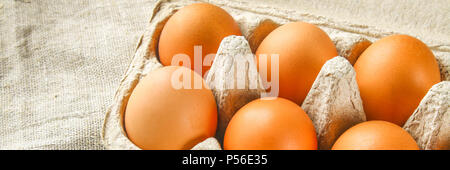 Raw braun huhn eier in einem Karton Fach mit Zellen auf Entlassung auf eine weiße Holztisch. Zutaten zum Kochen Stockfoto