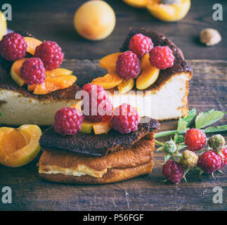 Stücke von Quark Torte mit Erdbeeren und Aprikosen auf einem braunen Holz- Board, in der Nähe Stockfoto