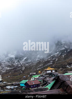 Einem nebligen Abend mit Hang dorf häuser am Nathang Tal, Indien. Stockfoto