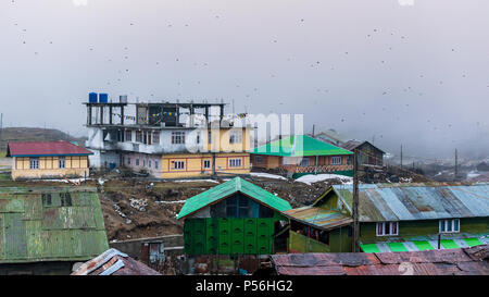 Einem nebligen Abend mit Hang dorf häuser am Nathang Tal, Indien. Stockfoto