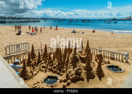 Cascais, Portugal - Juni 9, 2018: Man baut eine Sandburg an Praia da Ribeira Strand in Cascais, Portugal Stockfoto