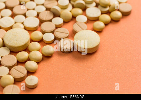 Haufen sortierte beige Kapseln auf orange Tabelle. Stockfoto