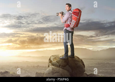 Gerne asiatische Touristen mit Kamera und Rucksack fertig ein Foto auf dem Berg zu nehmen Stockfoto