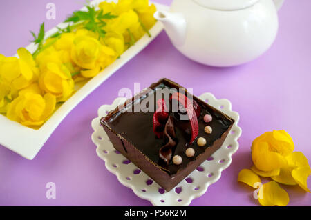 Hausgemachten Kuchen auf einem lila Hintergrund in einem Tee mit einem weißen Wasserkocher dienen. Stockfoto