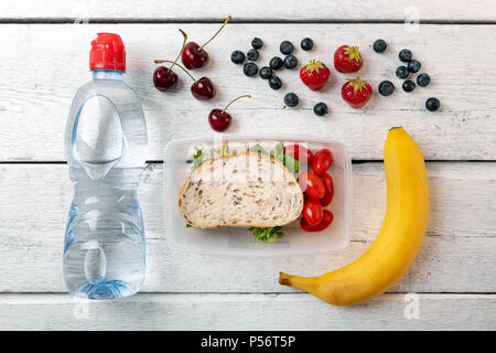 Lunchpaket mit Obst und Wasser Flasche auf weiße Holztisch Stockfoto
