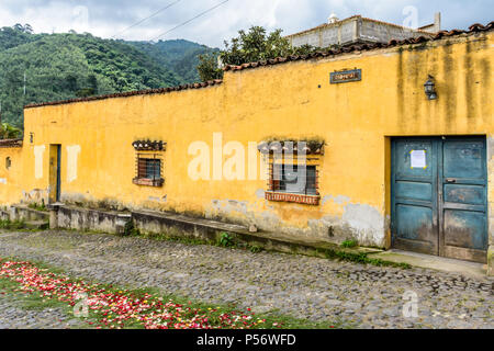 San Juan del Obispo, Guatemala - 25. Juni 2017: gelb gestrichenes Haus & Prozession Teppich für den Dorf Schutzpatron tag in der Nähe von Colonial Antigua. Stockfoto