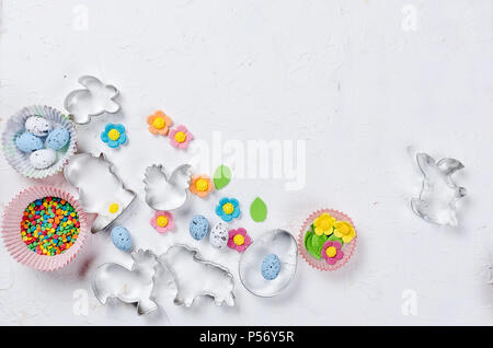 Ausstecher in Form von Symbol für Ostern - Hase, Ei, Huhn, bunte Eier und Zucker Streusel für Plätzchen und Kuchen, Ansicht von oben, kopieren Raum Cookin Stockfoto