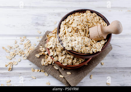 Haferflocken in Keramik Schüssel und Löffel aus Holz auf Weiß vintage Holz- Hintergrund, selektiver Fokus Kopie Raum, Ansicht von oben Stockfoto