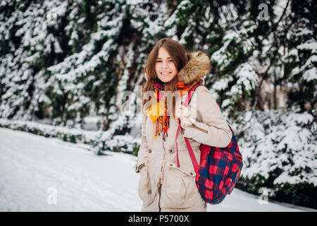 Thema ist das Wochenende Urlaub im Winter. Eine schöne Junge kaukasier Frau steht im Snow park in Jacke mit Kapuze und Fell in Jeans und lächelt mit Checker Stockfoto