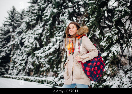 Thema ist das Wochenende Urlaub im Winter. Eine schöne Junge kaukasier Frau steht im Snow park in Jacke mit Kapuze und Fell in Jeans und lächelt mit Checker Stockfoto