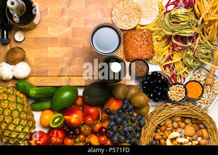Mediterrane Küche im Hintergrund. Auswahl von frischem Obst, Gemüse, Nüsse, Samen, Bohnen und Wein. Ansicht von oben Stockfoto