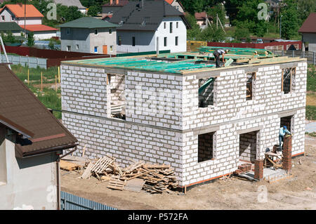 Der Bau des Hauses von einem weißen Stein, Festlegung eines Daches Stockfoto