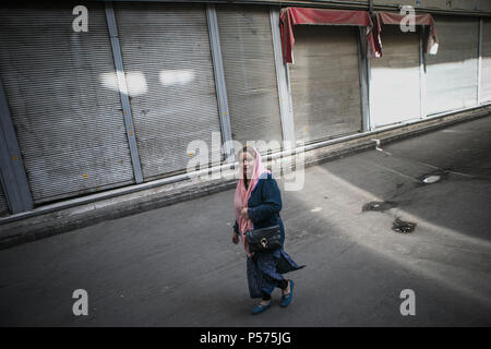 Teheran, Iran. 25. Juni 2018. Eine Frau geht Vergangenheit Geschäfte an der alten Main Bazaar in der Innenstadt von Teheran, Iran geschlossen, am 25. Juni 2018. Die Handelszentren im Großen Basar von Teheran geschlossen ihre Unternehmen aus Protest gegen die hohen Preise und instabilen Währungskurs. Credit: Ahmad Halabisaz/Xinhua/Alamy leben Nachrichten Stockfoto