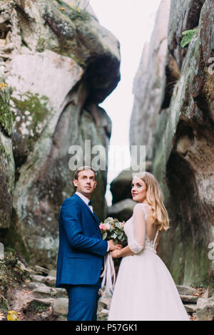 Brustbild der Jungvermählten zur Seite schauen beim Stehen auf dem Felsen. Stockfoto