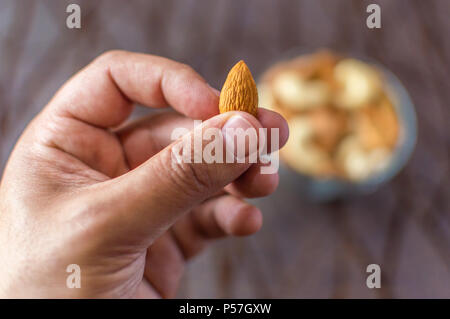 Eine Person angezeigt und bietet eine Mandel aus einer Schüssel Stockfoto