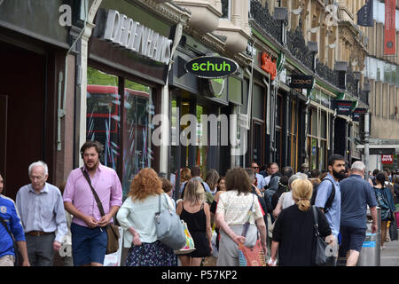 Käufer und Touristen zu Fuß entlang Magdalen Street, Oxford, wo High Street Einzelhändler wie Supermärkte Sainsbury's Lokale, Tesco Metro, der Schuh r Stockfoto
