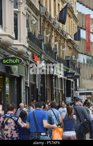 Käufer und Touristen zu Fuß entlang Magdalen Street, Oxford, wo High Street Einzelhändler wie Supermärkte Sainsbury's Lokale, Tesco Metro, der Schuh r Stockfoto