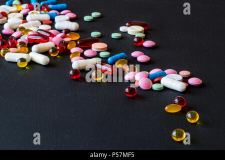 Verschiedene bunte Arzneimittel. Pillen und Kapseln auf schwarzem Hintergrund. Kopieren Sie Platz. Stockfoto