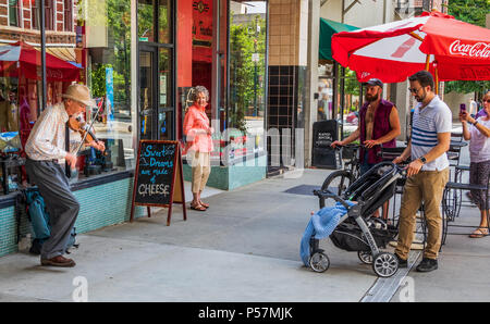 ASHEVILLE, NC, USA-24. Juni 18: ein Senior street Musiker eine Geige spielen, tanzen und singen, während Sie von mehreren Personen beobachtet. Stockfoto