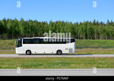 Weiß Coach bus Fahrt auf der Autobahn an einem sonnigen Tag des Sommers, Seitenansicht. Stockfoto