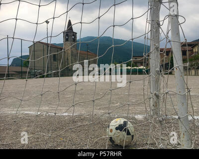 Eine alte Fußball in ein Ziel lag auf einem harten Pitch im Italienischen Dorf… Stockfoto
