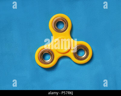 Gelbe zappeln Spinner auf dem blauen Gewebe Hintergrund Stockfoto