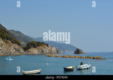 Kleine Boote mit Außenbordmotoren sind in einer ruhigen Bucht vor Anker. Eine Mole und einer kleinen Insel sind vor Ihnen, und felsige Hügel zur Seite. der Himmel Stockfoto