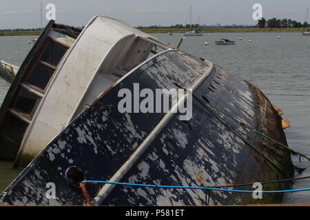 Küstenlandschaften - Verfall - einem Gekenterten Boot Wrack auf der linken Seite auf der Website von seiner letzten Verankerung liegt. Essex, Großbritannien Stockfoto