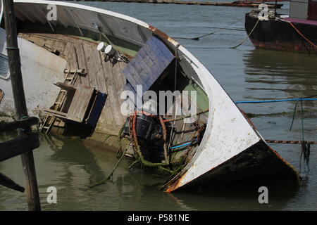 Küstenlandschaften - Verfall - einem Gekenterten Boot Wrack auf der linken Seite auf der Website von seiner letzten Verankerung liegt. Essex, Großbritannien Stockfoto