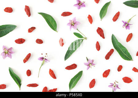 Nahaufnahme der Goji Beeren, Lycium Barbarum. Getrocknete asiatische Früchte, Blätter und Blüten auf weiß Holz- Hintergrund isoliert. Gesunde superfood. Floralen Muster. Flatlay, Ansicht von oben. Stockfoto