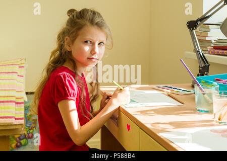 Adorable Mädchen, 7 Jahre alt, zeichnet Aquarell am Tisch zu Hause. Kind Kreativität, Erholung, Entwicklung. Stockfoto