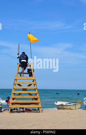 Ein Rettungsschwimmer wacht aus einem Wachturm an der North Avenue Beach in Chicago an einer gelben Flagge Warnung von rauhem Wasser Bedingungen. Stockfoto