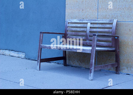 Shabby Chic Bank gegen eine blau und beige moderne Mauer aus Stein auf einer Stadt Bürgersteig set vermittelt ein kühles monochromatischen suchen Stockfoto