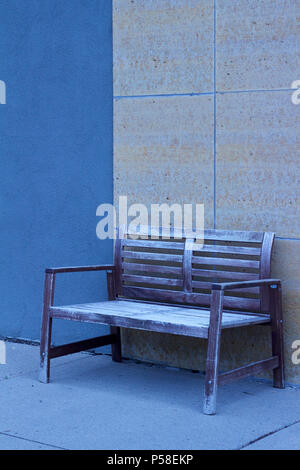 Shabby Chic Bank gegen eine blau und beige moderne Mauer aus Stein auf einer Stadt Bürgersteig set vermittelt ein kühles monochromatischen suchen Stockfoto