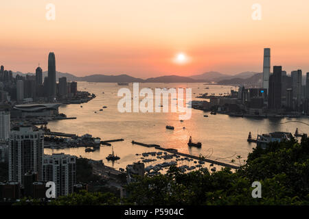 Einen atemberaubenden Blick auf den Sonnenuntergang über dem Victoria Harbour in Hong Kong mit der Wolkenkratzer von Hong Kong Island und Kowloon in den Links auf der rechten Seite Stockfoto