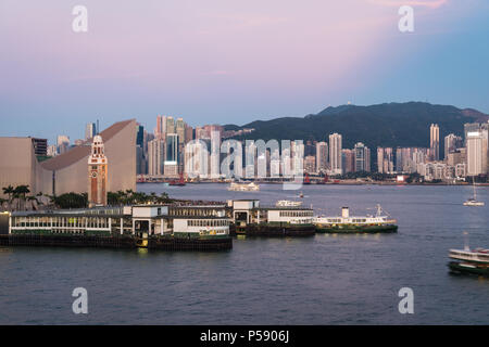 Die Star Ferry Pier in Tsim Sha Tsui in Kowloon mit Blick auf die Skyline von Hong Kong Island im Hintergrund über dem Victoria Harbour in Hong Kong, China Stockfoto