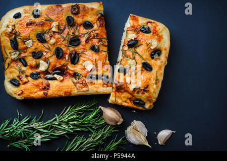 Home Italienisch Focaccia mit Oliven und Rosmarin auf schwarzen Hintergrund. Ansicht von oben Stockfoto