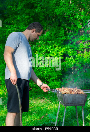 Schöner mann Vorbereitung Grill für Freunde outdoor. Stockfoto