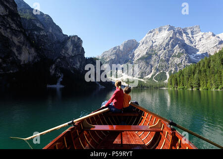 Mutter und Sohn Rudern in einem Holzboot auf einem Berg gelegen mit einem herrlichen Blick über die Berge; Lago di Braies; Dolomiti, Italien Stockfoto