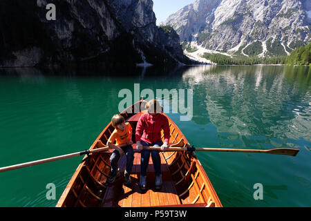 Mutter und Sohn Rudern in einem Holzboot auf einem Berg gelegen mit einem herrlichen Blick über die Berge; Lago di Braies; Dolomiti, Italien Stockfoto