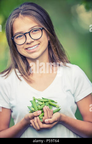 Lächelnden jungen Mädchen, dass in Ihrer Hand frische Erbsen. Stockfoto