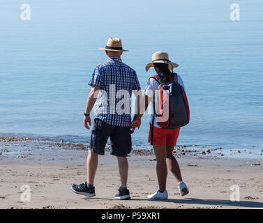 Lyme Regis, Dorset, Großbritannien. 26. Juni 2018. UK Wetter: Sehr heiß und sonnig in Lyme Regis. Ein paar nehmen Sie morgens einen Spaziergang am Strand entlang in der heißen Sonne im Badeort Lyme Regis am heißesten Tag des Jahres so weit. Credit: Celia McMahon/Alamy Leben Nachrichten. Stockfoto