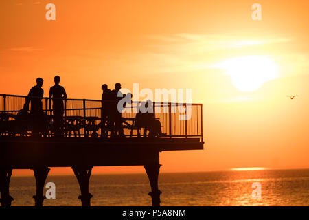 Aberystwyth, Großbritannien. 26 Juni, 2018. UK UK Wetter: einen spektakulären Sonnenuntergang über dem Meer Pier und Cardigan Bay in Aberystwyth am Ende eines Tages, wenn die Temperatur auf 28 °C in der Stadt und über 30 c in Porthmadog, gerade lang der Küste im Norden von Wales die britische Position wird in einem mini Hitzewelle mit Temperaturen weit über 30 Grad Celsius prognostiziert durch die Mittwoch oder Donnerstag Photo Credit: Keith Morris/Alamy leben Nachrichten Stockfoto