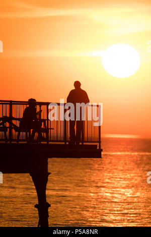 Aberystwyth, Großbritannien. 26 Juni, 2018. UK UK Wetter: einen spektakulären Sonnenuntergang über dem Meer Pier und Cardigan Bay in Aberystwyth am Ende eines Tages, wenn die Temperatur auf 28 °C in der Stadt und über 30 c in Porthmadog, gerade lang der Küste im Norden von Wales die britische Position wird in einem mini Hitzewelle mit Temperaturen weit über 30 Grad Celsius prognostiziert durch die Mittwoch oder Donnerstag Photo Credit: Keith Morris/Alamy leben Nachrichten Stockfoto